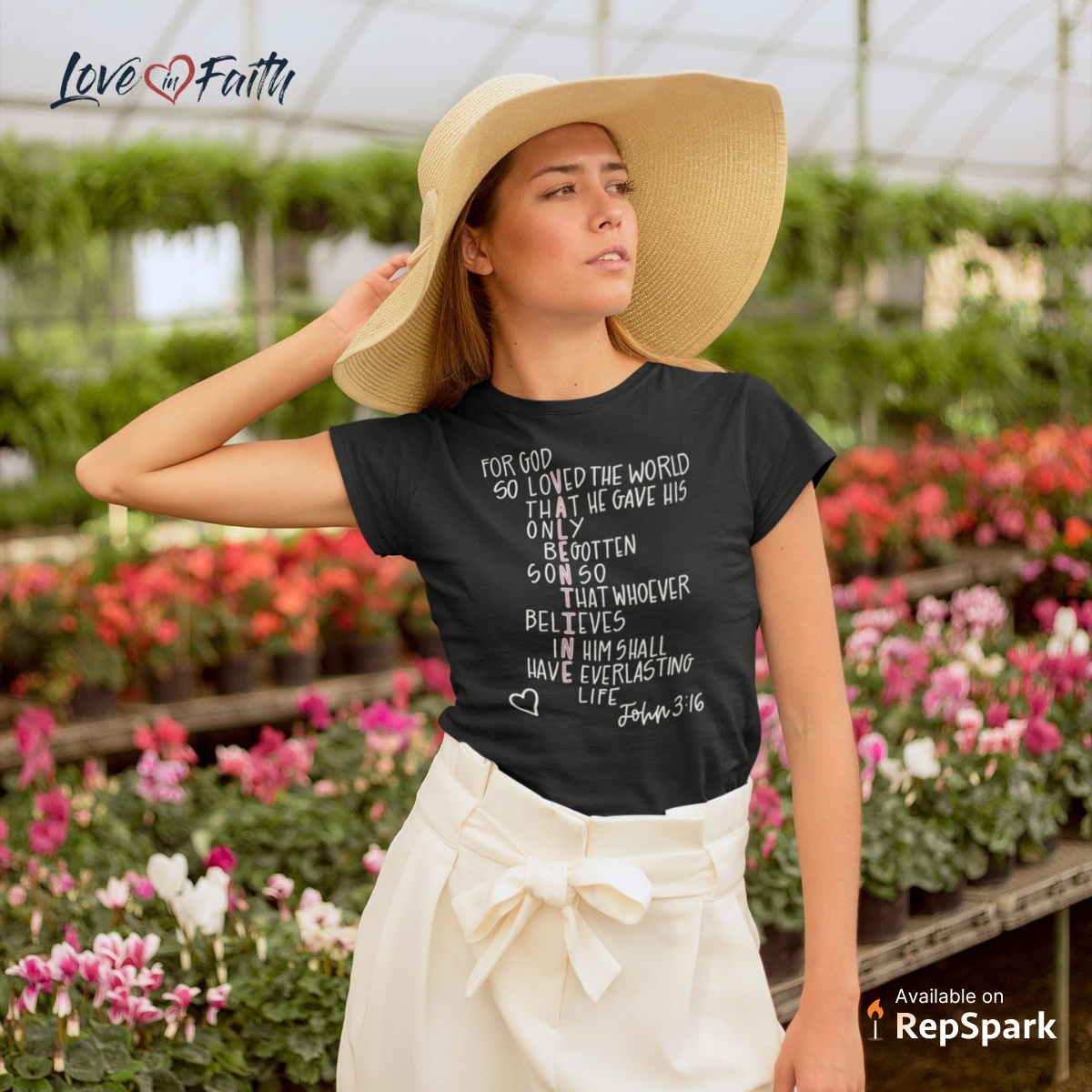 Woman standing in a flower field wearing a woven hat and black faith t-shirt.