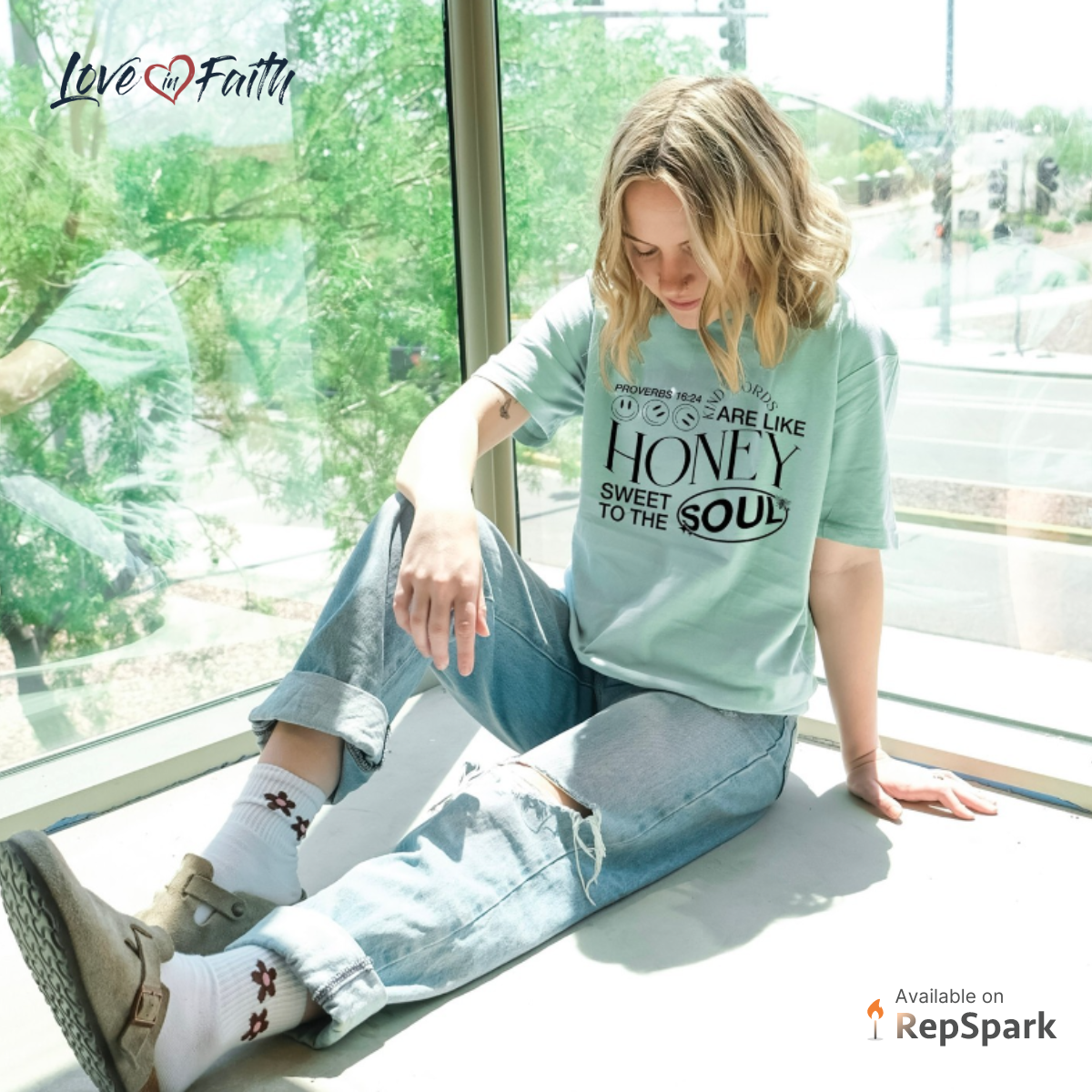 Woman sitting on a window sill wearing birkenstocks, ripped jeans, and a faith t-shirt.