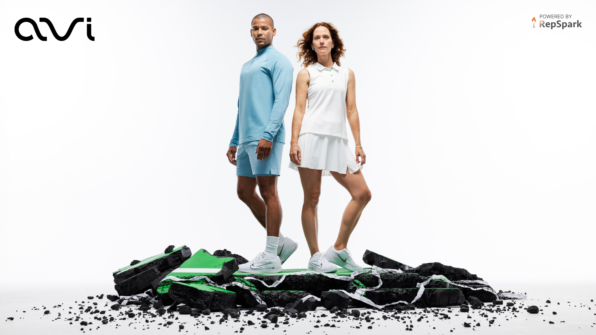 A man in a blue athletic set and a woman in a white athletic set standing on a racquet court of rubble. 