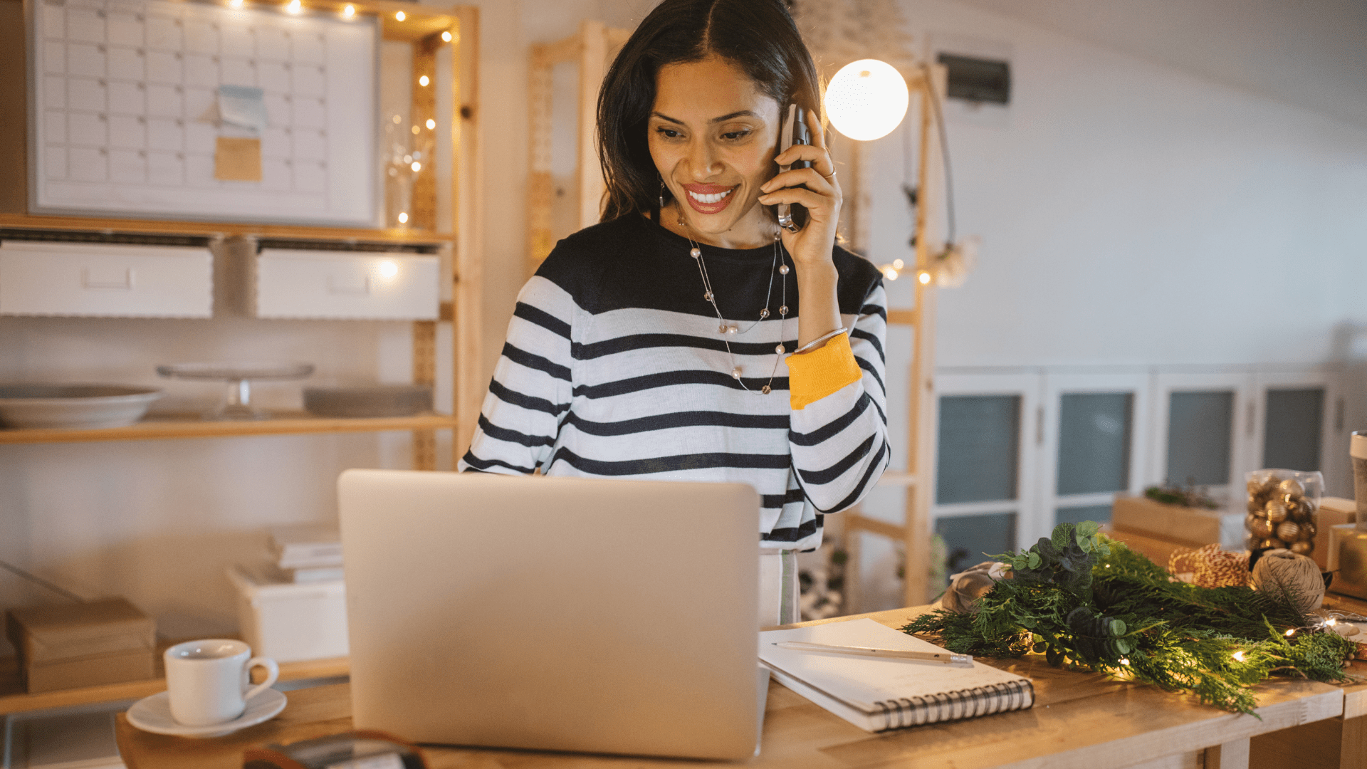 Professional woman multitasking, placing an online order on her laptop while engaged in a phone conversation