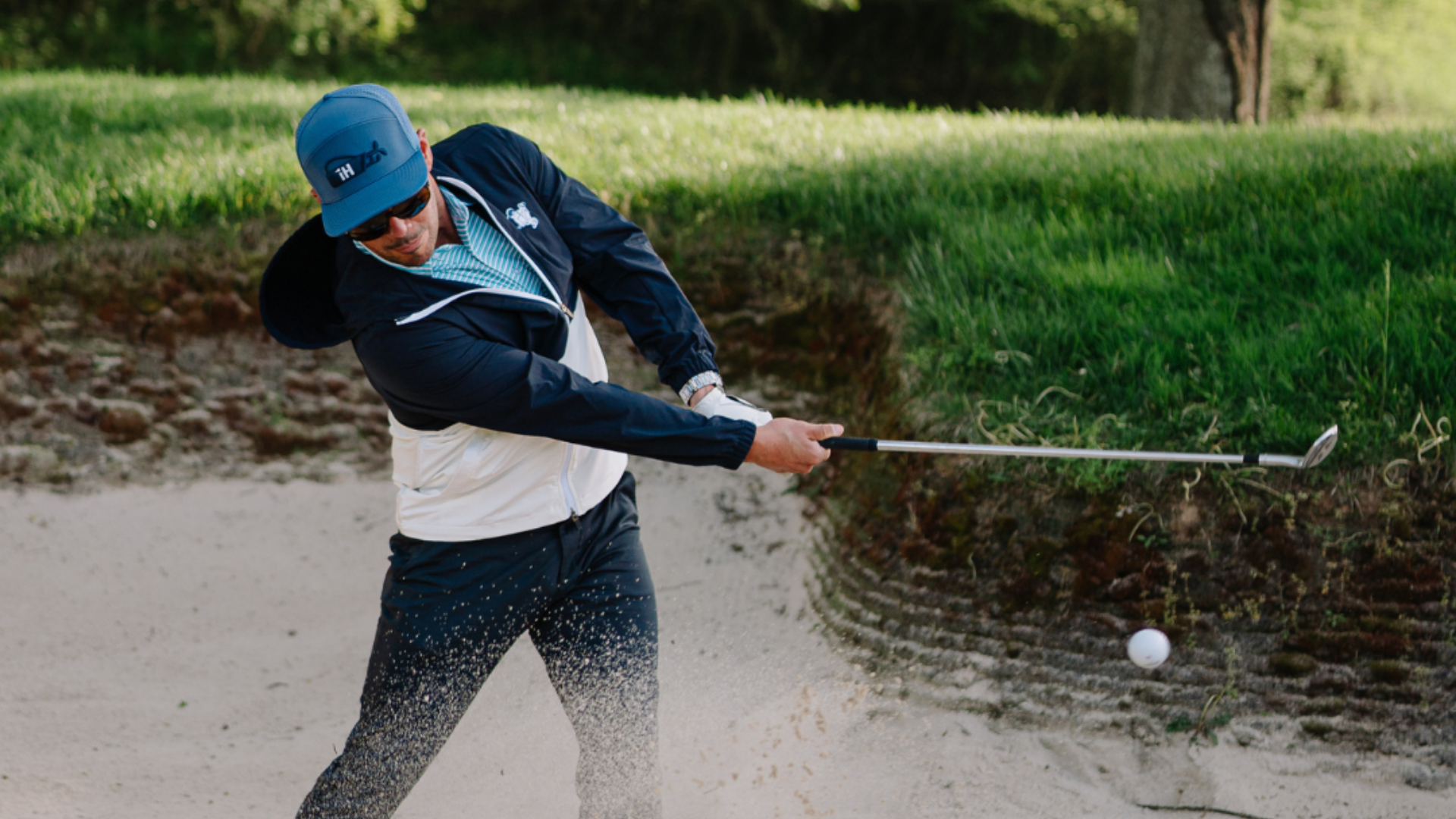 Man in a Bunker driving his golf ball out of the sand trap. 