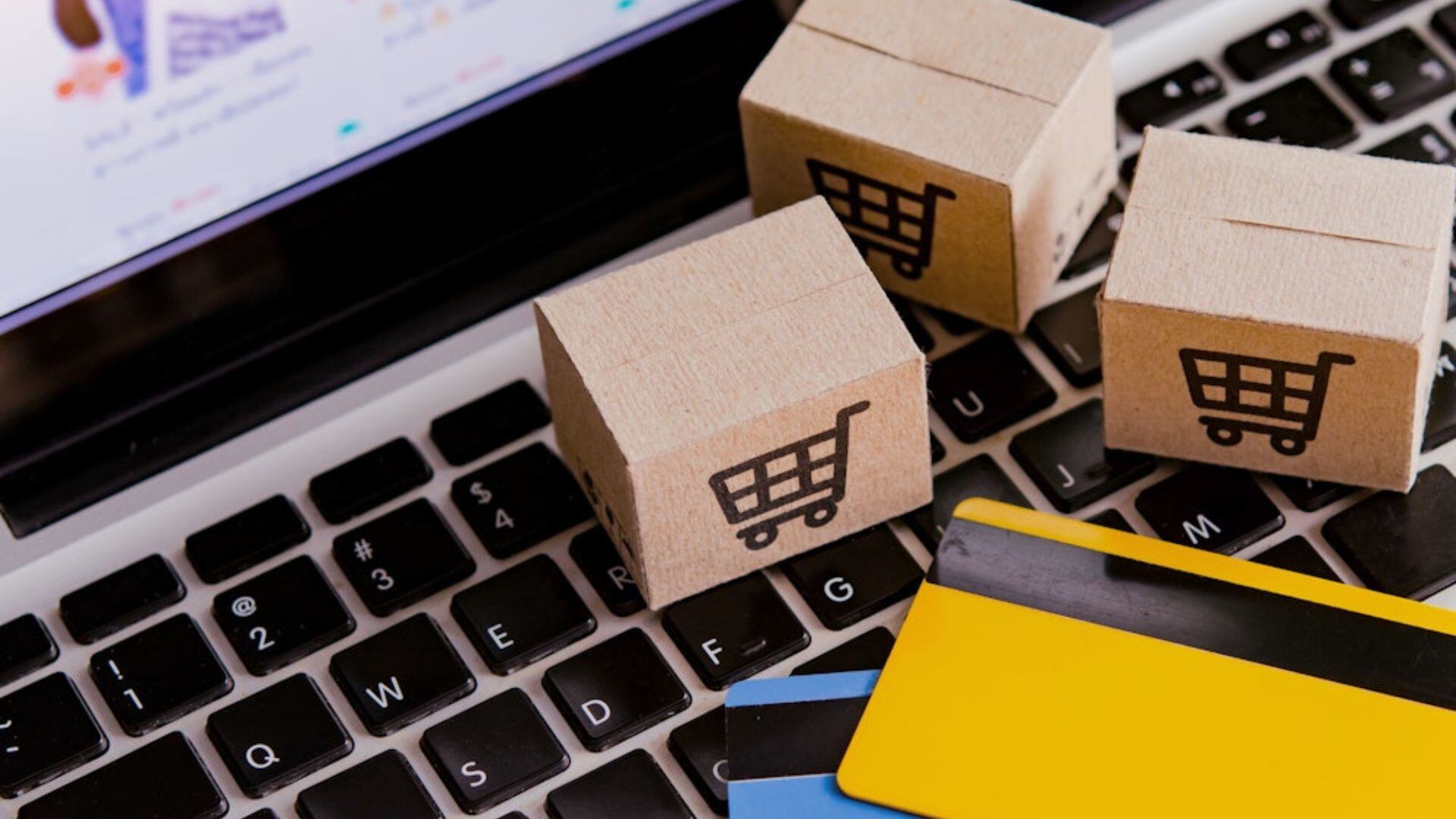 miniature checkout boxes and credit cards on top of a macbook keyboard