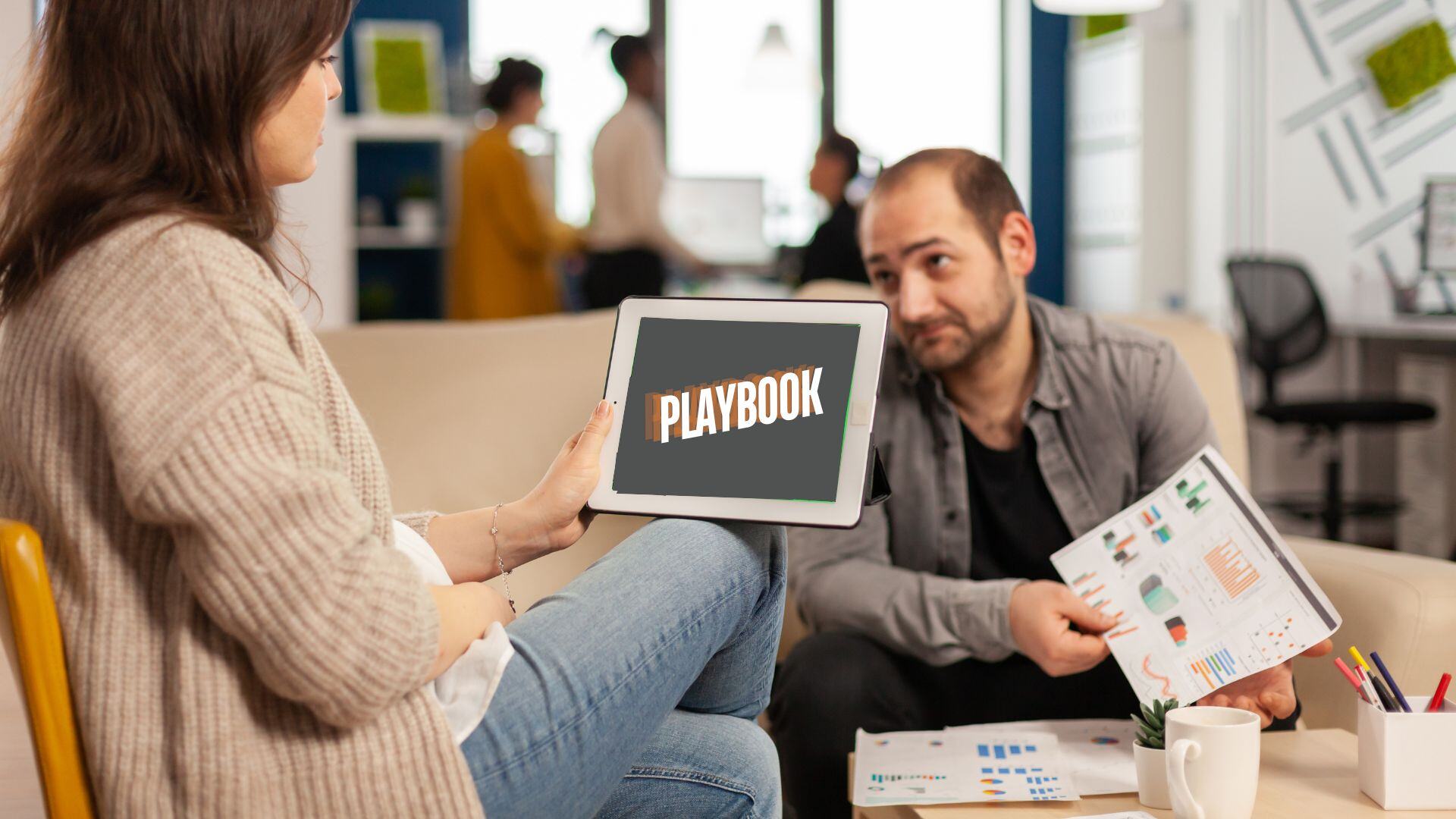 man and women reviewing an ipad that has the word playbook on it