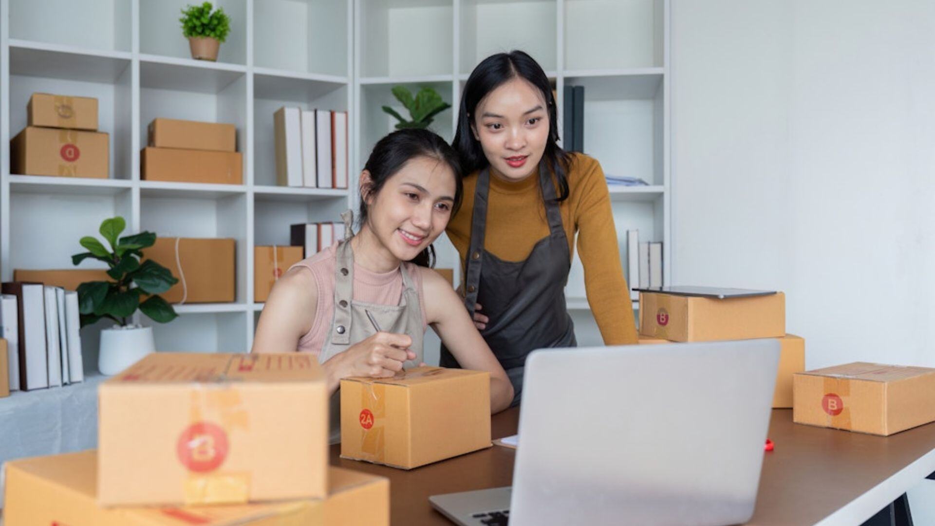 two women looking at a laptop learning how to streamline their wholesale operations