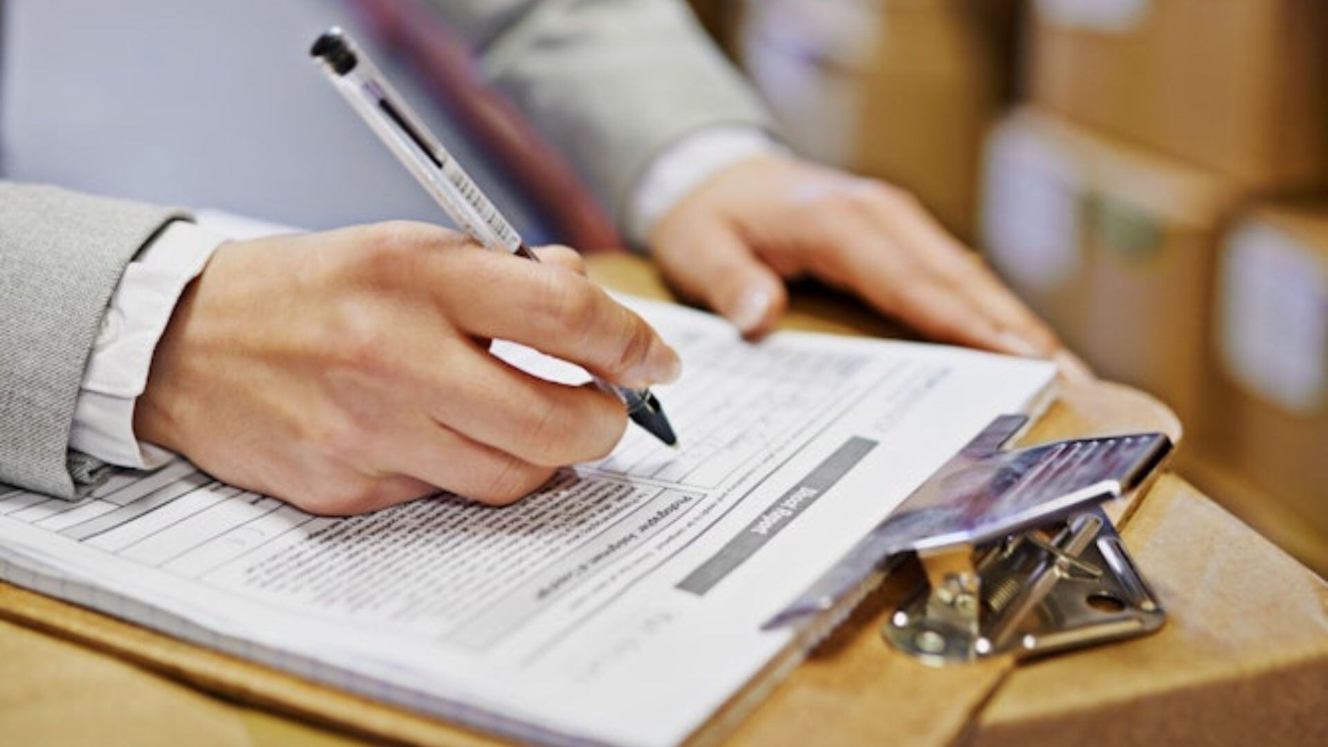 a close up shot of a clipboard with payment terms and hands with pen in and ready to sign